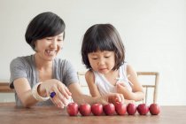 Mother and daughter with red apples in a row — Stock Photo
