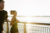 Jogging couple running along riverside early morning — Stock Photo