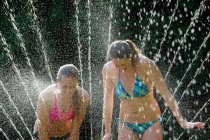 Teenage girls playing in sprinkler — Stock Photo