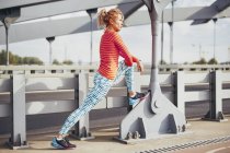 Молода жінка бігун розігрівається на міському пішохідному мосту — стокове фото