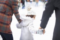 Rear view of girl ice skating with parents, holding hands — Stock Photo
