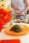 Piatto di asparagi con pancetta con donna da pranzo sullo sfondo — Foto stock