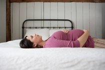 Schwangere liegt auf Bett — Stockfoto