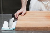 Primo piano della mano del macellaio con tagliere e coltello — Foto stock