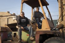 Колеги на будівельному майданчику сидять на важких машинах — стокове фото