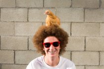 Портрет мальчика-подростка с рыжими афро-волосами, курица сидит на голове — стоковое фото