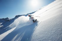 Лыжник спускается вниз зимой — стоковое фото
