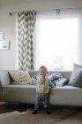 Portrait of toddler boy standing beside sofa — Stock Photo