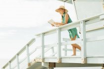 Mulher na torre salva-vidas revista de leitura — Fotografia de Stock