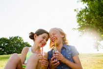 Lachende Mädchen, die draußen Saft trinken — Stockfoto
