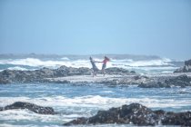 Ciudad del Cabo, Sudáfrica, pareja joven desde lejos, balanceándose unos a otros por los brazos en la playa - foto de stock