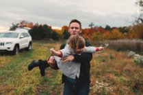 Hombre adulto medio jugando con su hija pequeña en el campo - foto de stock