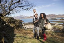 Familia a pie, padre llevando a su hijo en hombros, Loch Eishort, Isla de Skye, Escocia - foto de stock