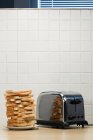 Stack of toasts and toaster on table — Stock Photo