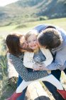 Mid adult couple kissing daughter's cheeks in field — Stock Photo