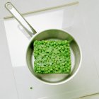 Frozen peas in saucepan — Stock Photo