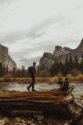 Чоловічий турист на верхівці падаючого стовбура дерева, що дивиться на гори, Національний парк Йосеміті, штат Каліфорнія, США. — стокове фото