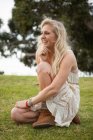 Усміхнена жінка сидить у полі — стокове фото