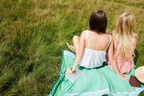 Молодые женщины сидят вместе в поле — стоковое фото