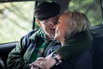 Старшая пара обнимается на заднем сиденье машины — стоковое фото