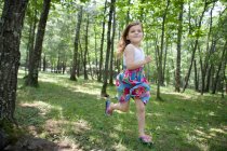 Pequena menina feliz correndo na floresta — Fotografia de Stock
