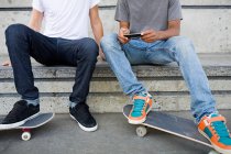 Мальчики-подростки со скейтбордами и мобильными телефонами — стоковое фото