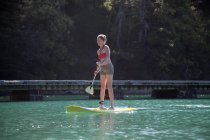 Mulher adulta média levantar-se paddleboarding no mar — Fotografia de Stock