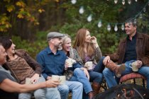 Smiling friends outdoors by fire — Stock Photo