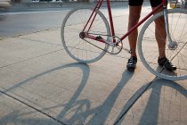Cropped image of Cyclist standing with bike on street — Stock Photo