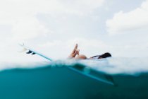 Surface level view of woman lying on surfboard, Oahu, Hawaii, USA — Stock Photo