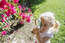 Young girl looking through magnifying glass — Stock Photo