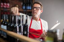 Cape Town, South Africa, young male wine shopkeeper reaching out for bottle — Stock Photo