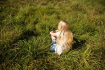 Молодая женщина мирно сидит в поле — стоковое фото