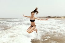 Девушка в бикини тянет ноги вверх в прыжке — стоковое фото