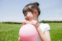 Girl with pink balloon in th meadow — Stock Photo