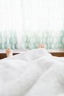 Pair of feet sticking out under duvet — Stock Photo
