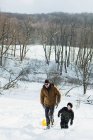 Pai e filho escorregando na neve — Fotografia de Stock