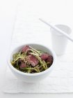 Bowl of beef and green tea noodles served with chopsticks — Stock Photo