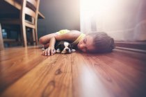Girl lying on floor with sleeping Boston Terrier puppy — Stock Photo