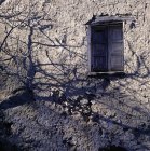 Shuttered window in stone wall with shadows — Stock Photo