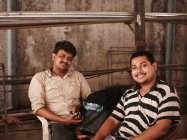 Улыбающиеся мужчины сидят в сарае — стоковое фото