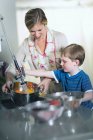 Mother and son washing vegetables in sink at home — Stock Photo