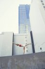 Mujer joven al aire libre, de pie en la pared en posición de yoga - foto de stock