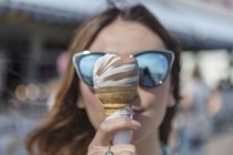 Close up of ice creme cone being held by woman in sunglasses — Stock Photo
