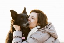 Крупный план средней взрослой женщины целующей свою собаку — стоковое фото