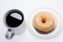 Кава і пончик на тарілці — стокове фото