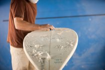 Cropped image of Man waxing surfboard — Stock Photo