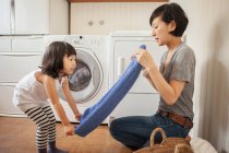 Mother and daughter folding towel — Stock Photo