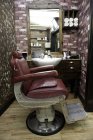 Вид сбоку на бордовое кожаное кресло в парикмахерской — стоковое фото