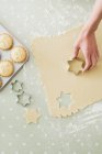 Cropped image of woman making star shaped cookies with cookie cutter — Stock Photo